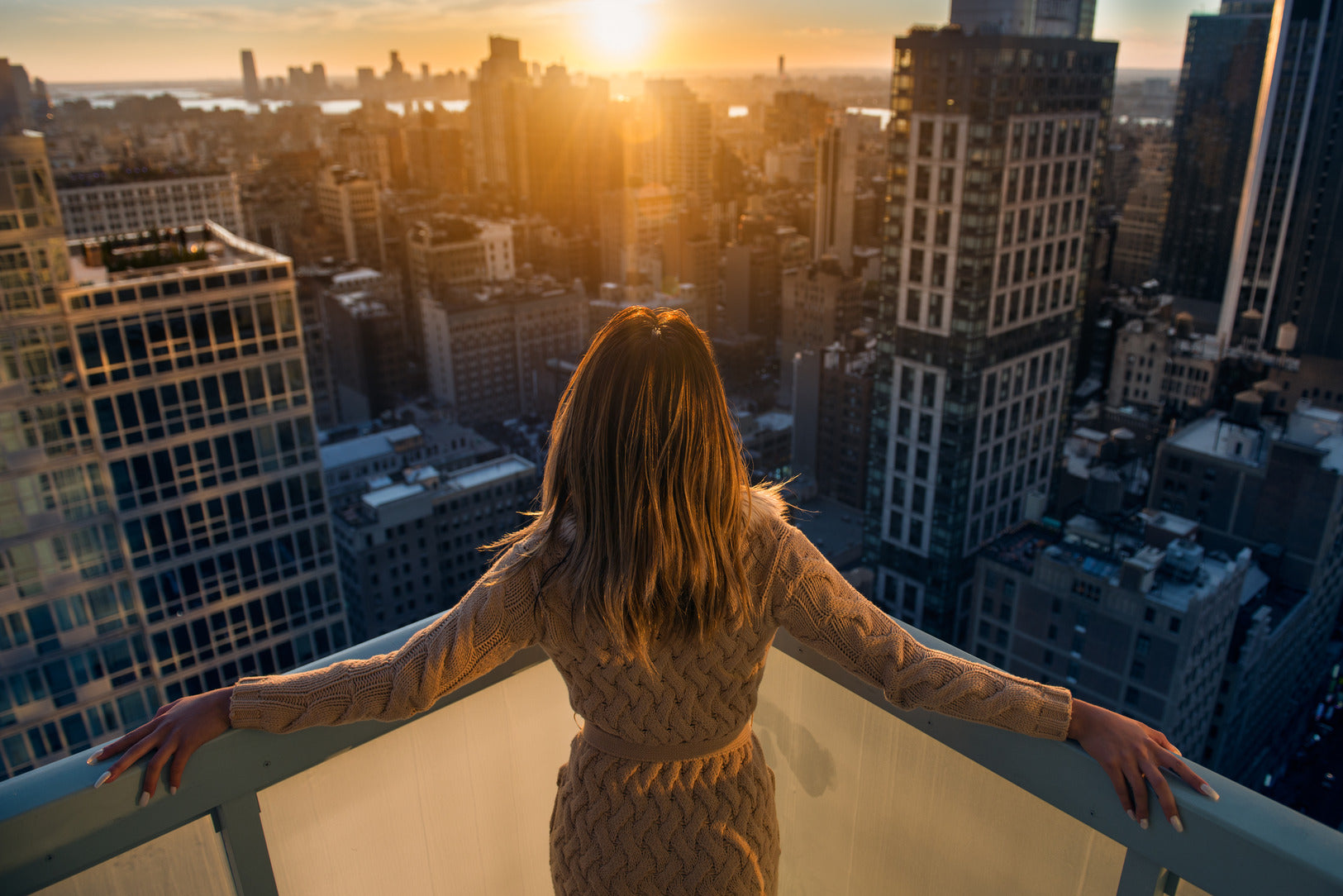 businesswoman standing on a balcony in a luxury apartment in new york city